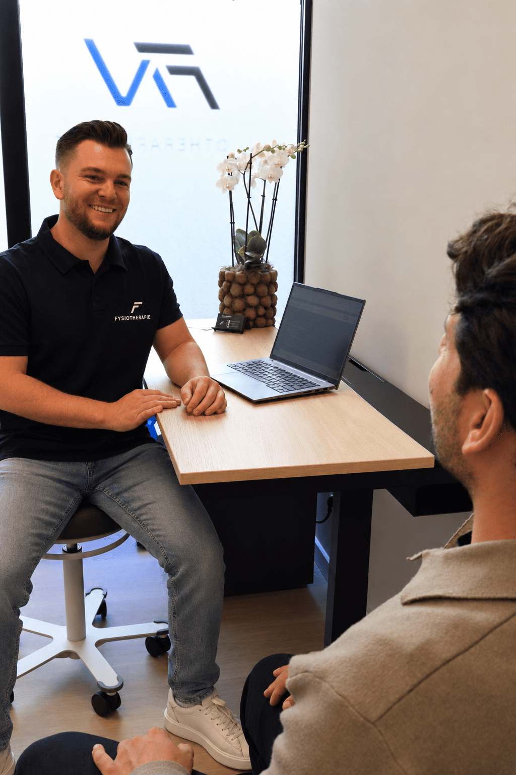 Fysiotherapeut in gesprek met een client in de spreekkamer