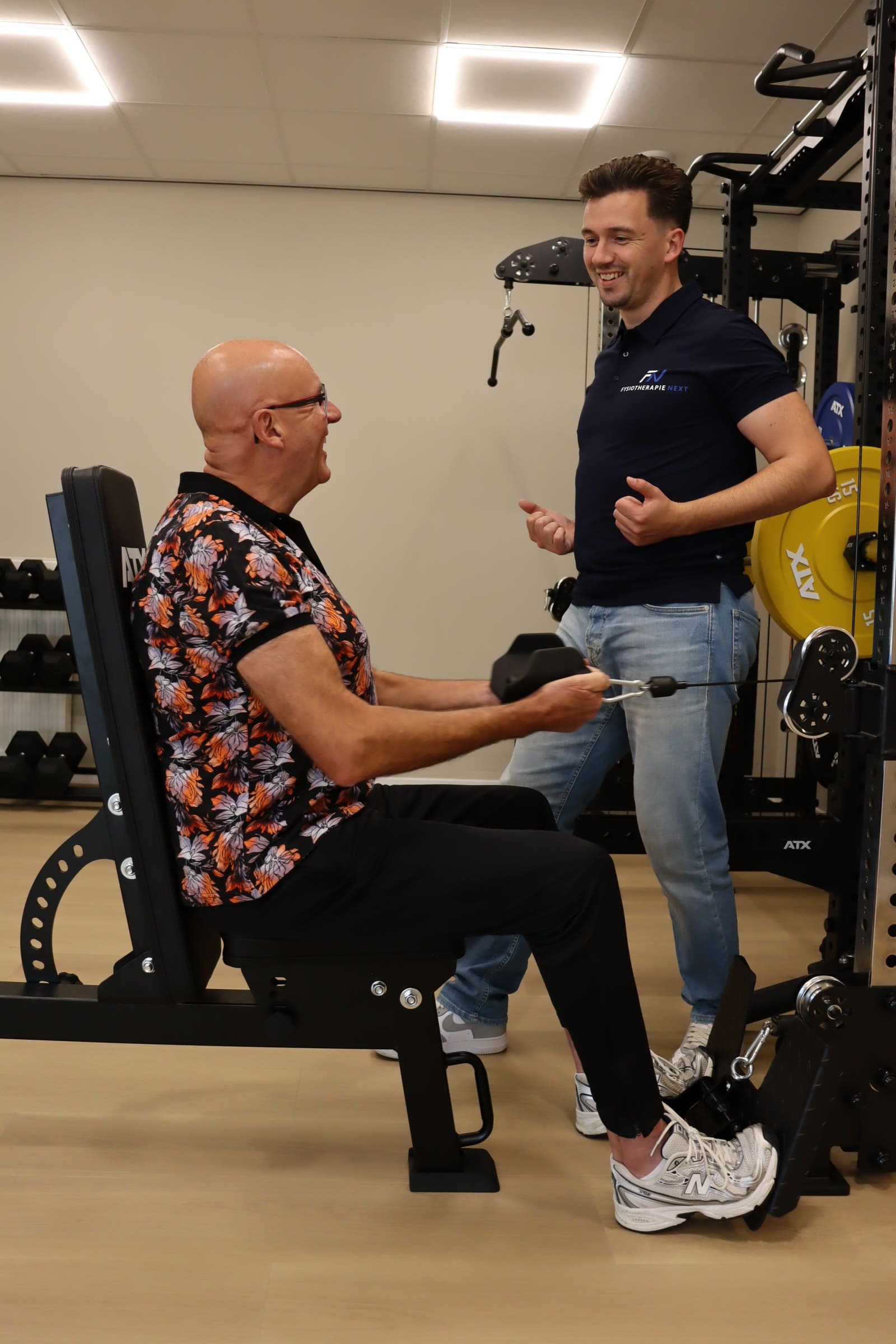 Fysiotherapeut geeft uitleg aan een client op een trainingstoestel